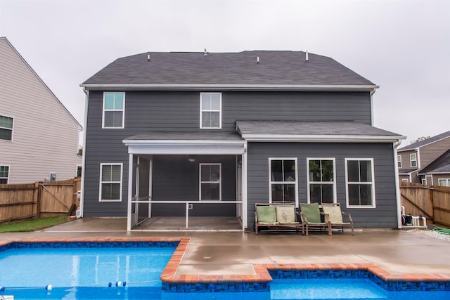 rear view of property featuring a sunroom, a patio area, and a fenced in pool