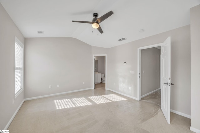 unfurnished bedroom featuring ceiling fan, ensuite bathroom, lofted ceiling, and light carpet