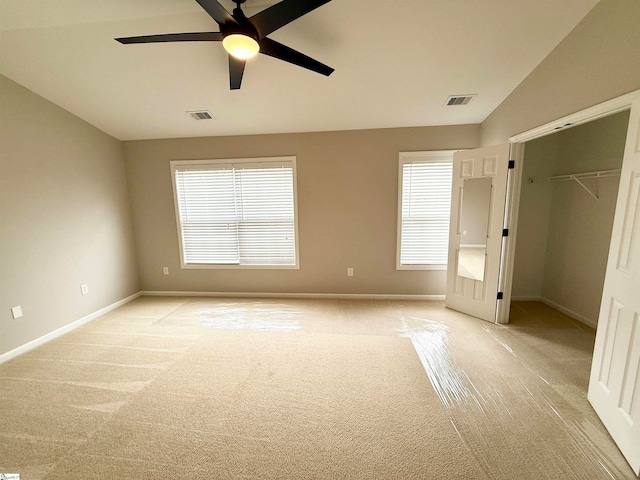 unfurnished bedroom with ceiling fan, a spacious closet, lofted ceiling, light carpet, and a closet