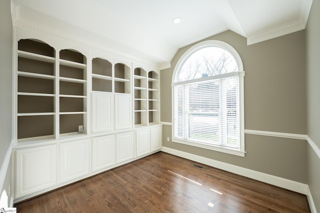 empty room with crown molding, dark wood-type flooring, and vaulted ceiling