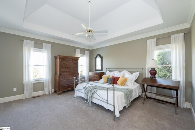 carpeted bedroom featuring a raised ceiling, multiple windows, and ceiling fan