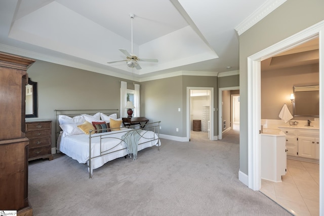 carpeted bedroom with ensuite bathroom, sink, ceiling fan, ornamental molding, and a tray ceiling