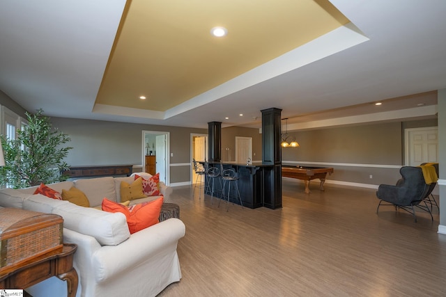 living room featuring bar, a raised ceiling, dark wood-type flooring, and pool table