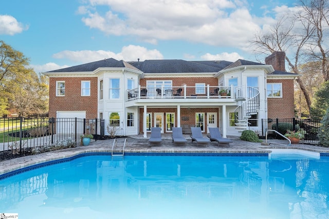 rear view of house with a pool side deck and a garage