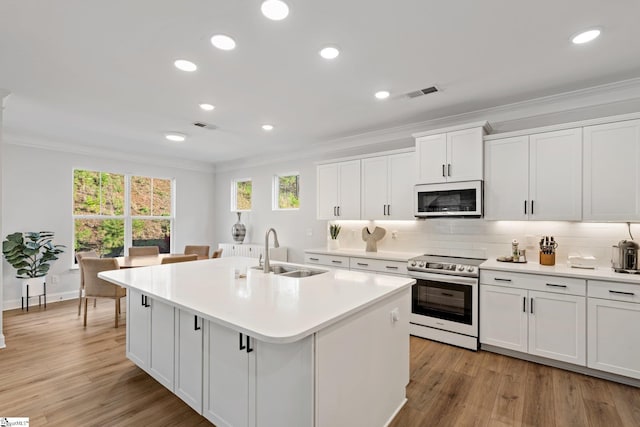 kitchen with sink, stainless steel appliances, an island with sink, light hardwood / wood-style floors, and white cabinets