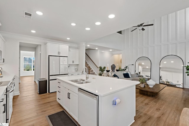 kitchen with dishwashing machine, sink, white refrigerator, a center island with sink, and white cabinetry