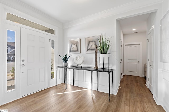 foyer entrance featuring a wealth of natural light, crown molding, and light hardwood / wood-style floors