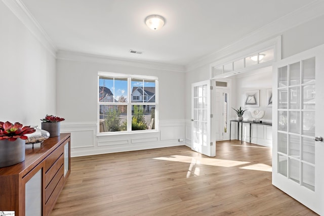 interior space featuring light wood-type flooring, crown molding, and french doors