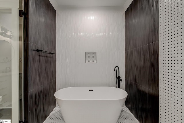 bathroom featuring tile patterned flooring, a bath, and tile walls