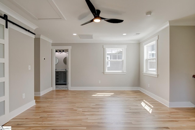 unfurnished living room with a barn door, light hardwood / wood-style floors, ceiling fan, and crown molding