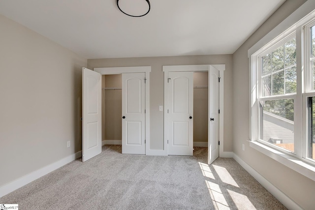 unfurnished bedroom with light carpet and two closets