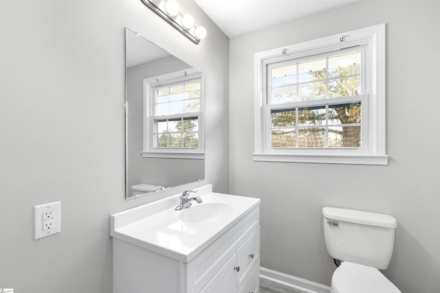 bathroom with plenty of natural light, toilet, a textured ceiling, and vanity