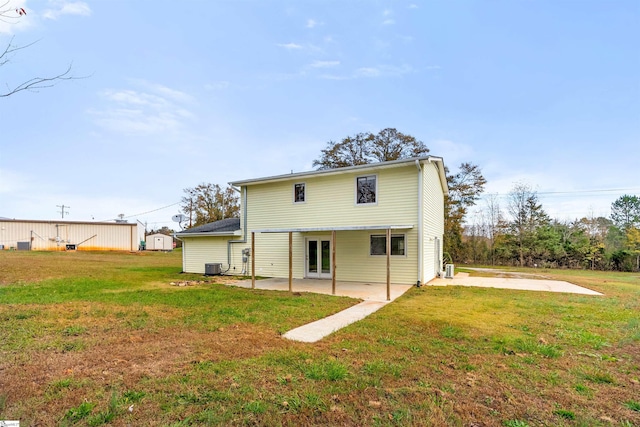 rear view of property with a lawn, central AC unit, and a patio area