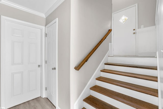 staircase with wood-type flooring and ornamental molding