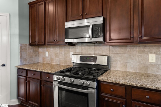 kitchen with decorative backsplash, appliances with stainless steel finishes, and light stone counters