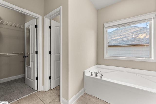 bathroom with a tub to relax in and tile patterned floors