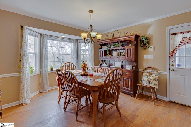 dining room with a chandelier, light hardwood / wood-style floors, and crown molding