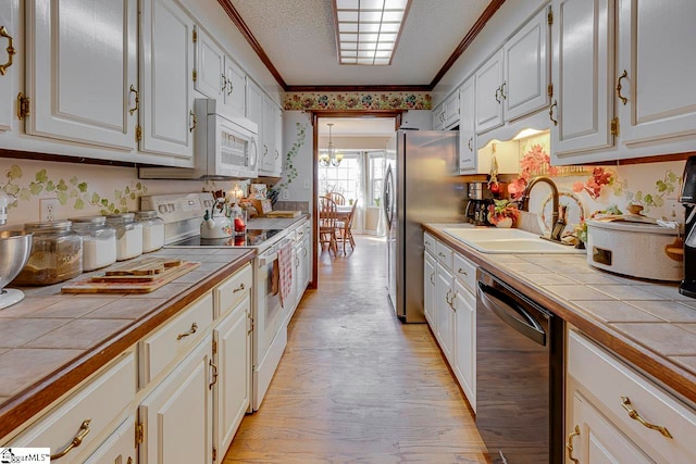 kitchen featuring white cabinets, appliances with stainless steel finishes, light hardwood / wood-style flooring, and tile counters