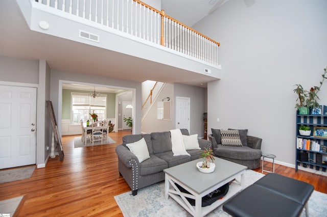 living room with a high ceiling, an inviting chandelier, and wood-type flooring