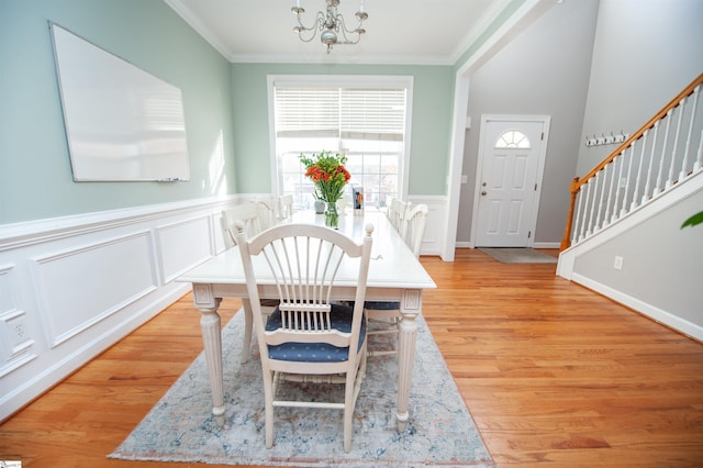 dining area with a chandelier, ornamental molding, and light wood-type flooring