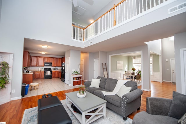 living room with light hardwood / wood-style floors, a high ceiling, and a chandelier