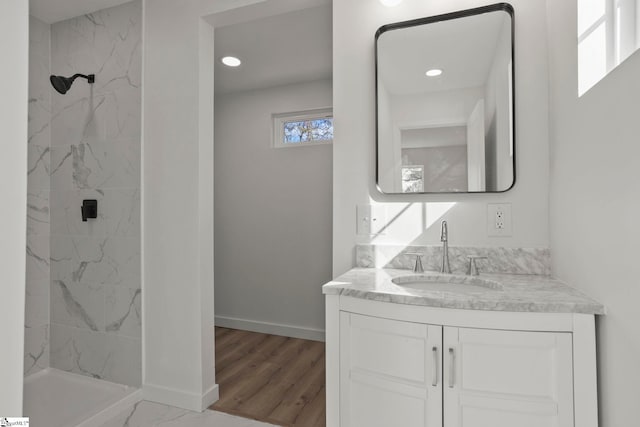 bathroom featuring a tile shower, vanity, and wood-type flooring