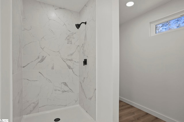 bathroom with a tile shower and hardwood / wood-style flooring