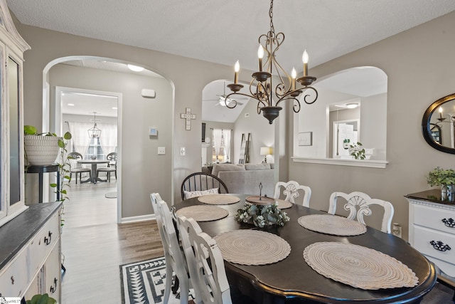 dining area featuring a textured ceiling, light hardwood / wood-style floors, and an inviting chandelier