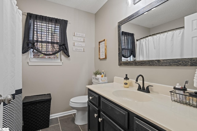 bathroom with tile patterned flooring, a textured ceiling, vanity, and toilet