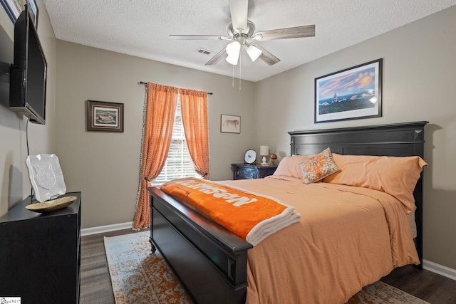 bedroom featuring ceiling fan, dark hardwood / wood-style flooring, and a textured ceiling