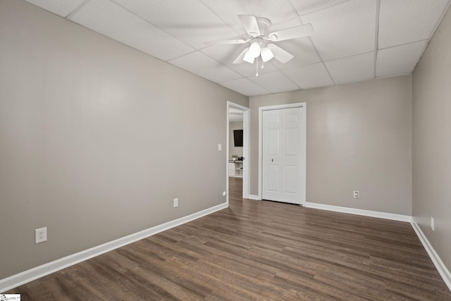 spare room featuring a paneled ceiling, ceiling fan, and dark wood-type flooring