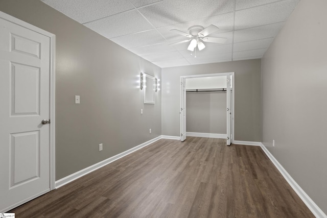 unfurnished bedroom with hardwood / wood-style floors, a paneled ceiling, a closet, and ceiling fan