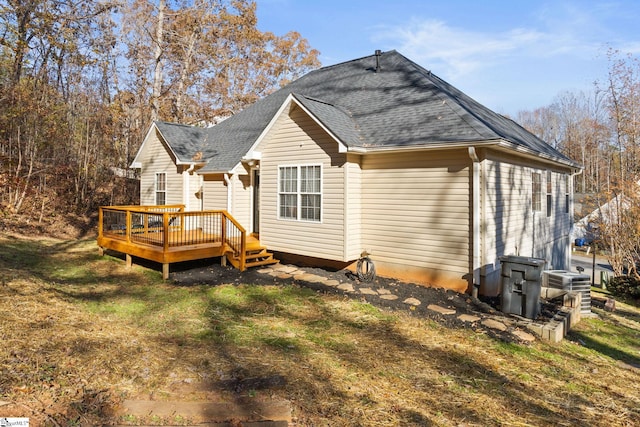 rear view of property with a deck, cooling unit, and a lawn