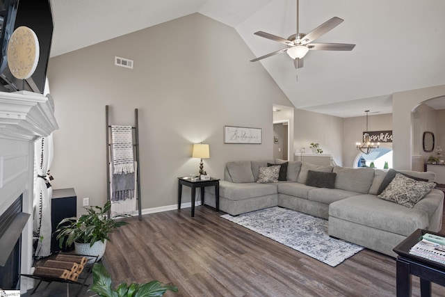 living room with ceiling fan with notable chandelier, dark hardwood / wood-style floors, and high vaulted ceiling