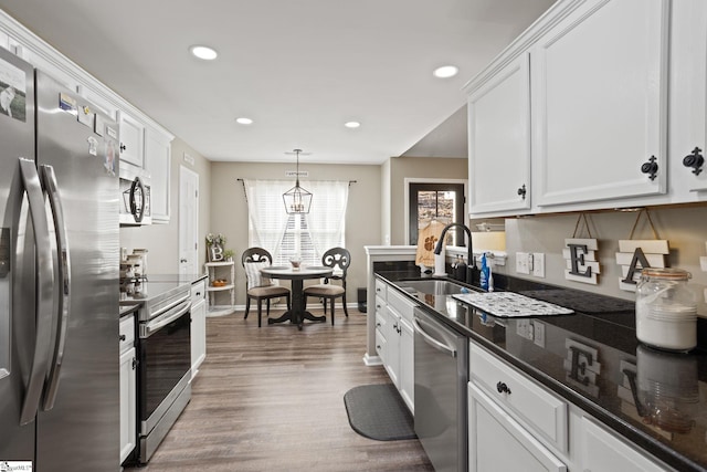 kitchen with sink, stainless steel appliances, wood-type flooring, decorative light fixtures, and white cabinets