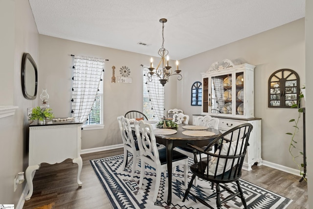 dining area with a chandelier, a textured ceiling, and dark hardwood / wood-style flooring