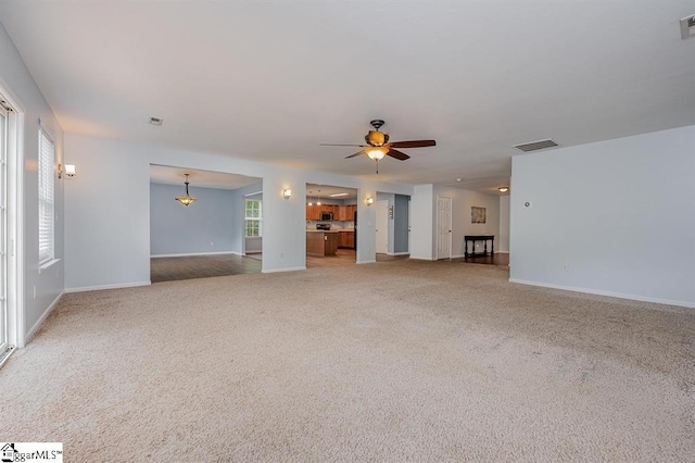 unfurnished living room featuring light colored carpet and ceiling fan