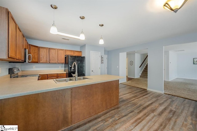 kitchen with kitchen peninsula, stainless steel appliances, sink, decorative light fixtures, and hardwood / wood-style flooring