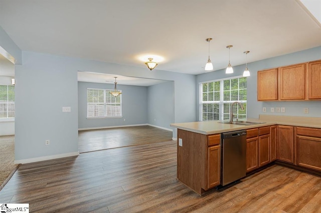 kitchen with sink, stainless steel dishwasher, kitchen peninsula, hardwood / wood-style floors, and pendant lighting