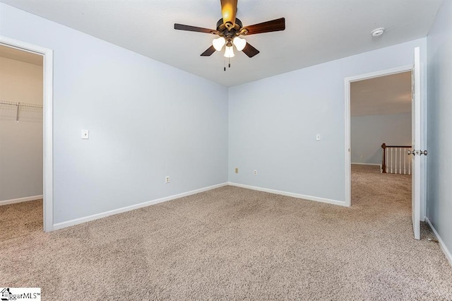 unfurnished bedroom with a closet, light colored carpet, a spacious closet, and ceiling fan