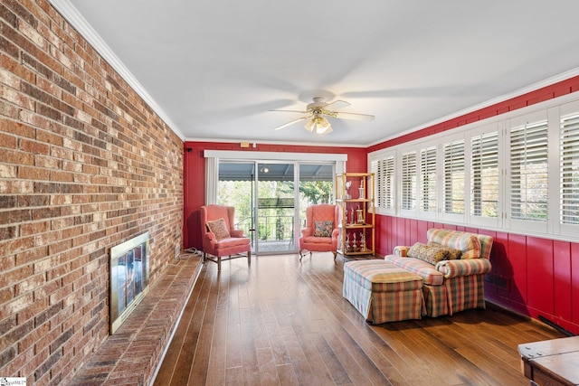 living room with hardwood / wood-style flooring, a brick fireplace, ceiling fan, and ornamental molding