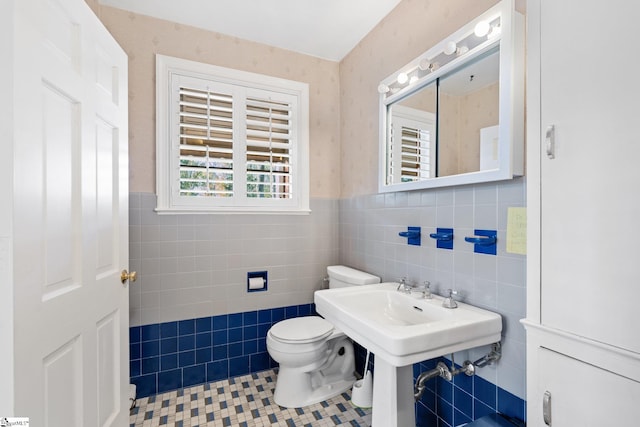 bathroom featuring tile patterned flooring, toilet, and tile walls