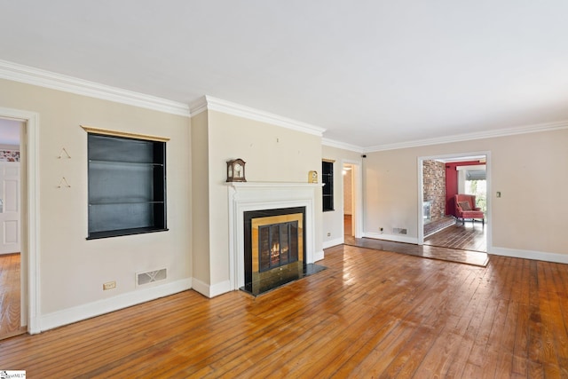 unfurnished living room featuring hardwood / wood-style flooring and crown molding