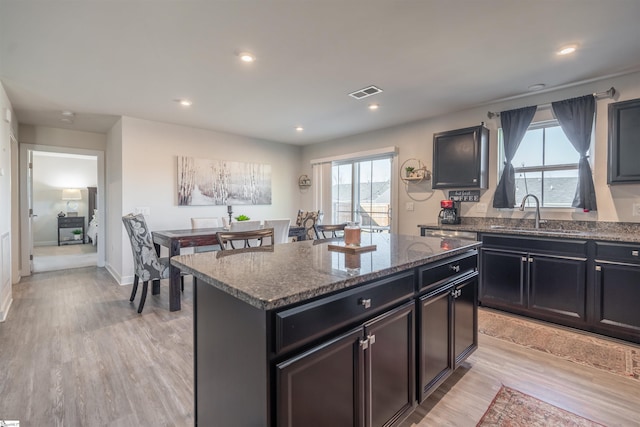 kitchen with light wood-type flooring, a center island, plenty of natural light, and sink