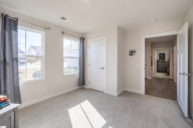 unfurnished bedroom with multiple windows and light carpet