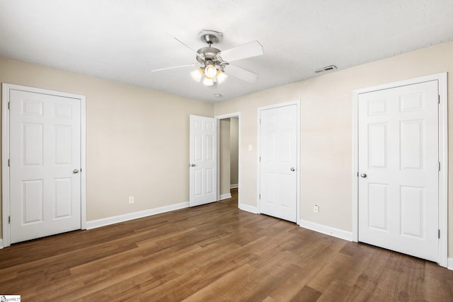 unfurnished bedroom featuring multiple closets, ceiling fan, and hardwood / wood-style floors