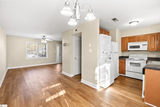 kitchen featuring stacked washer / drying machine, light hardwood / wood-style floors, white appliances, and hanging light fixtures