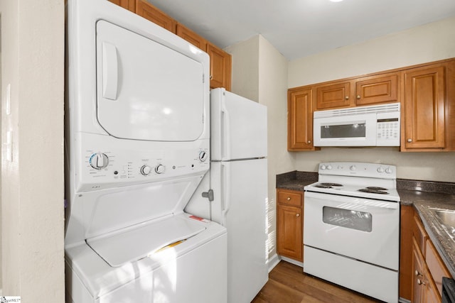 kitchen featuring stacked washing maching and dryer, dark hardwood / wood-style flooring, and white appliances