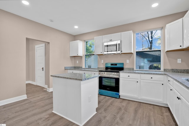 kitchen with a center island, white cabinets, light wood-type flooring, light stone counters, and stainless steel appliances