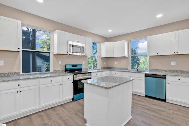 kitchen featuring white cabinets, appliances with stainless steel finishes, light hardwood / wood-style flooring, and light stone counters